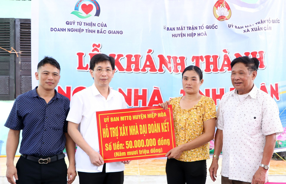 Đại diện Ủy ban MTTQ huyện Hiệp Hòa trao kinh phí hỗ trợ xây nhà đại đoàn kết cho gia đình chị Tạ Thị Huệ ở thôn Xuân Biều, xã Xuân Cẩm. Ảnh: PHƯƠNG NHUNG.